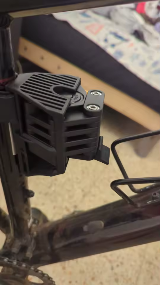 Lock in its bracket next to a bottle cage on a bike frame